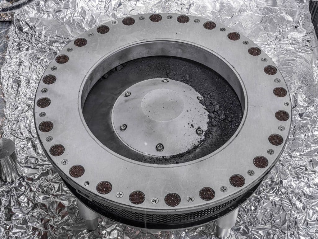 Una vista del exterior del recolector de muestras OSIRIS-REx. En el centro a la derecha se pueden ver muestras del asteroide Bennu. Los científicos han encontrado evidencia de carbono y agua en el análisis inicial de este material. La mayor parte de la muestra se encuentra en el interior.