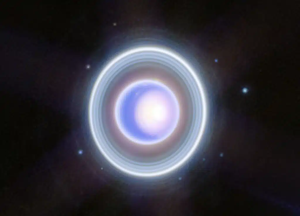 Esta imagen de Webb muestra 9 de las 27 lunas del planeta. Son los puntos azules que rodean los anillos del planeta. En el sentido de las agujas del reloj, a partir de las 2 en punto: Rosalind, Puck, Belinda, Desdemona, Cressida, Bianca, Portia, Juliet y Perdita. Las órbitas de estas lunas comparten la inclinación de 98 grados de su planeta madre en relación con el plano del Sistema Solar.