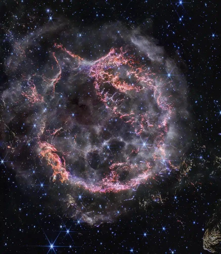 Nueva imagen en alta definición obtenida por la cámara NIRCam (cámara de infrarrojo cercano) del telescopio espacial James Webb. La imagen revela detalles intrincados del remanente de supernova Casiopea A (Cas A) y muestra la capa de material en expansión que choca contra el gas desprendido por la estrella antes de que explotara.