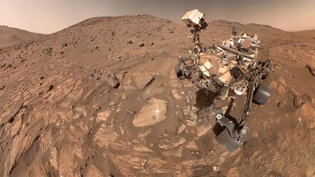Imagen tomada por el rover Perseverance el 23 de julio compuesta de 63 imágenes individuales. La roca "Chevaya Falls" se encuentra a la izquierda del rover, cerca del centro de la imagen.