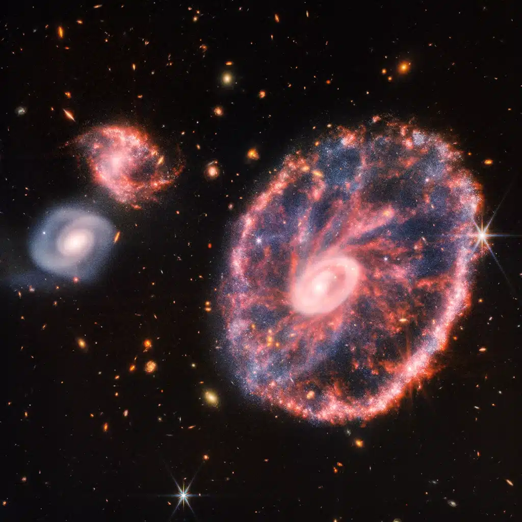 Imagen compuesta de la Galaxia "Rueda de Carro" y sus galaxias compañeras creada a partir de la Cámara de Infrarrojo Cercano (NIRCam) y el Instrumento de Infrarrojo Medio (MIRI) del telescopio Webb.