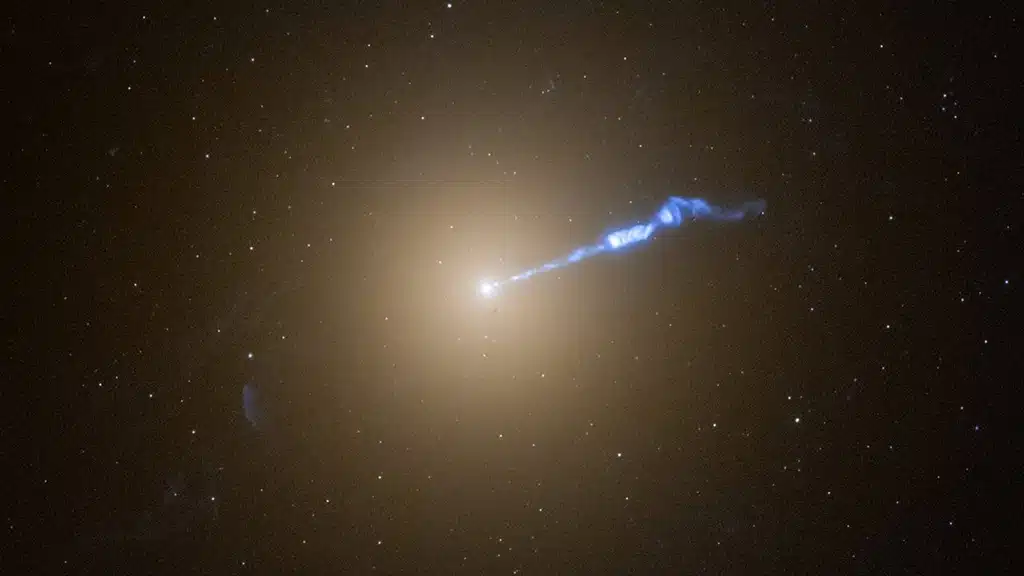 Imagen del Telescopio Espacial Hubble de la gigantesca galaxia M87 que muestra un chorro de plasma de 3 mil años luz de longitud, lanzado desde el agujero negro central de la galaxia, con una masa de 6.500 millones de soles. El chorro parece estar causando erupciones estelares a lo largo de su trayectoria.