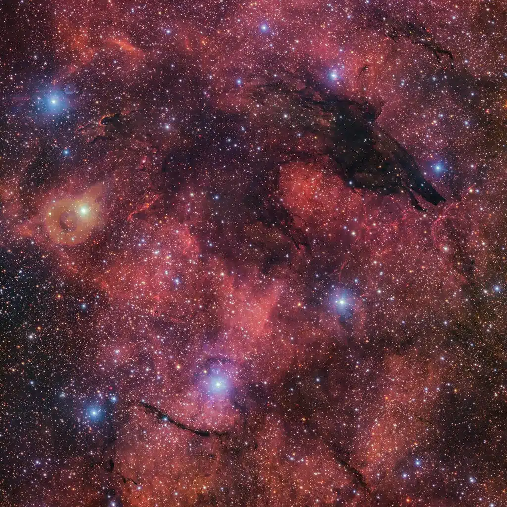 Nebulosa del Lobo Oscuro: Las frías nubes de polvo cósmico crean la ilusión de una silueta similar a la de un lobo sobre un colorido fondo de nubes de gas resplandeciente.