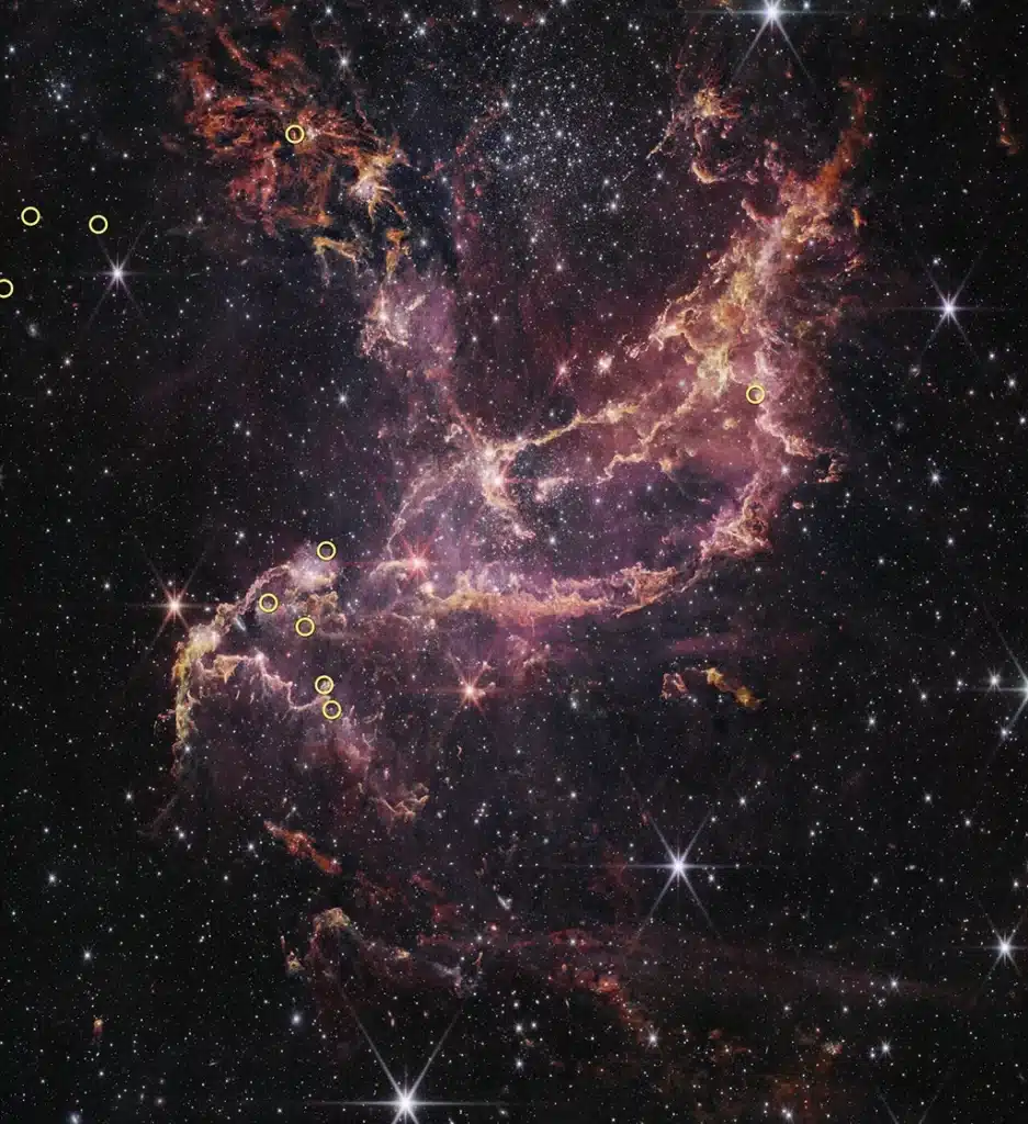 Imagen del Telescopio Espacial James Webb del cúmulo estelar NGC 346, un cúmulo masivo en la Pequeña Nube de Magallanes, una galaxia enana vecina cercana de la Vía Láctea. Con su relativa escasez de elementos más pesados que el helio y el hidrógeno, el cúmulo NGC 346 sirve como un análogo cercano para estudiar entornos estelares con condiciones similares a las del Universo temprano y distante. Diez pequeños círculos amarillos superpuestos en la imagen indican las posiciones de las diez estrellas analizadas en este estudio.