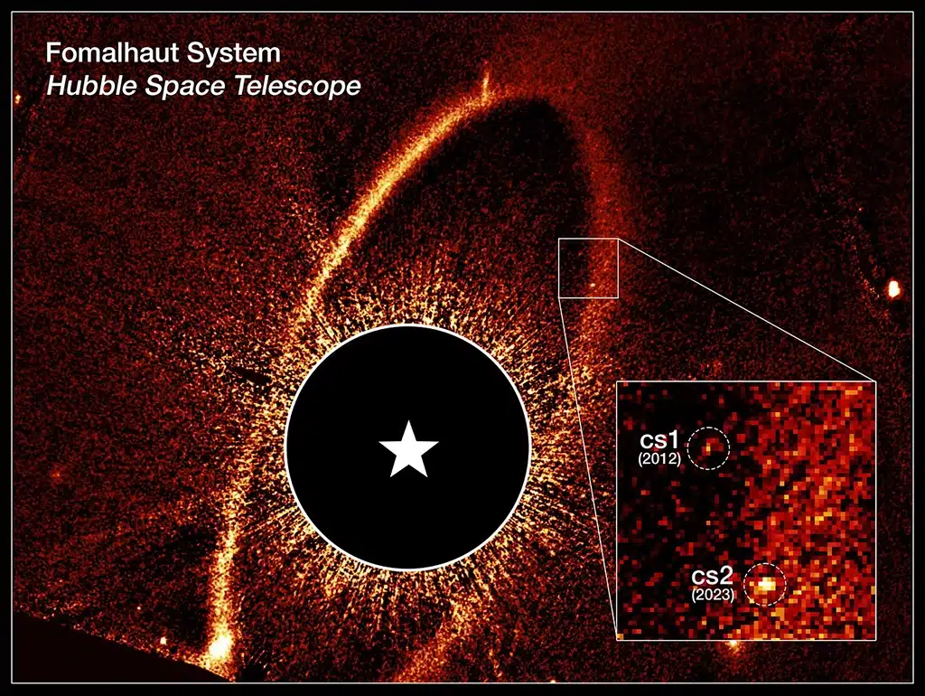 Imagen compuesta del telescopio Hubble que muestra el anillo de escombros y las nubes de polvo cs1 y cs2 alrededor de la estrella Fomalhaut. La nube de polvo cs1, observada en 2012, aparece junto a la nube de polvo cs2, observada en 2023. Los círculos discontinuos marcan la ubicación de estas nubes. Cuando la nube de polvo cs2 apareció repentinamente, los astrónomos advirtieron rápidamente que habían sido testigos de la violenta colisión de dos objetos masivos. Anteriormente considerada un planeta, cs1 se clasifica ahora como una nube de escombros similar a cs2. La estrella Fomalhaut ha sido ocultada para permitir la visualización de las estructuras más tenues. Su posición está indicada por la estrella blanca.