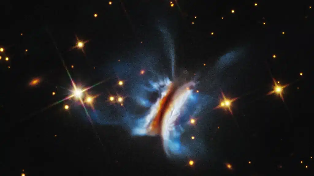 Imagen del Telescopio Espacial Hubble del mayor disco protoplanetario jamás observado alrededor de una estrella joven. Filamentos brillantes se extienden muy por encima y por debajo del disco, más de lo observado en cualquier otro disco circumestelar similar.